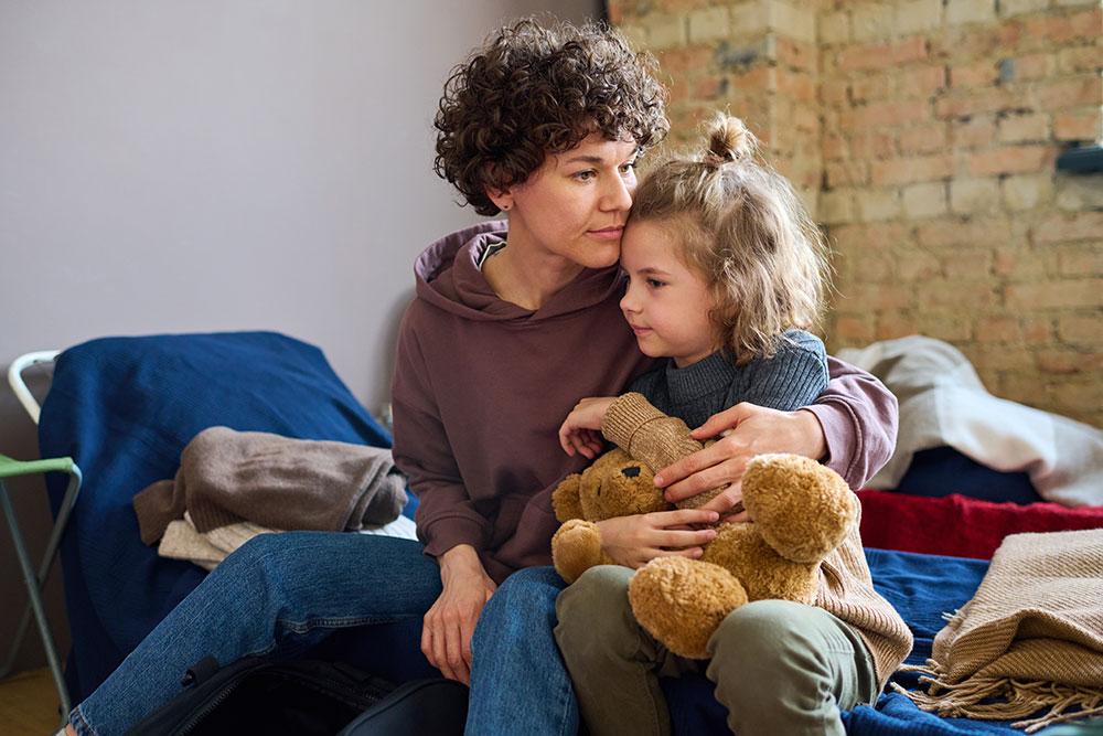 woman embracing child with teddy bear