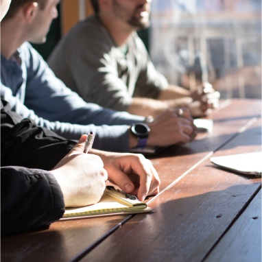 group of people at desk writing on paper