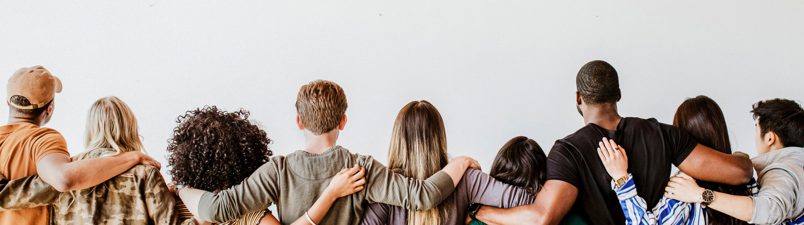 group of people with arms around each other facing away